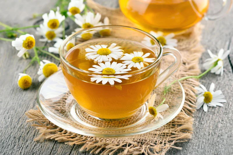 Tea pot with herbal tea and a slice of lemon on a wooden board